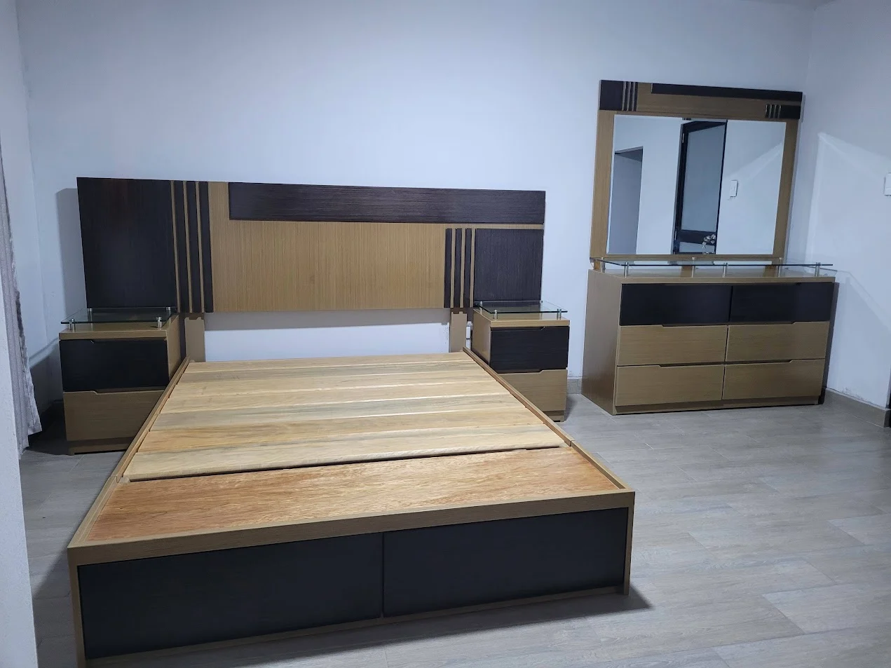 Juego de dormitorio de Creaciones Joaquín con cama sin colchón, dos veladores y cómoda con espejo.